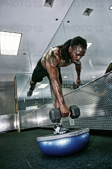 African American man lifting weights in gym