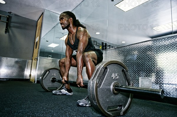 African American man lifting weights in gym