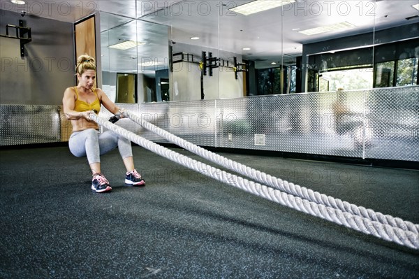 Caucasian woman working out with ropes in gym