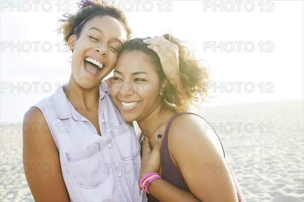 Smiling friends hugging at beach