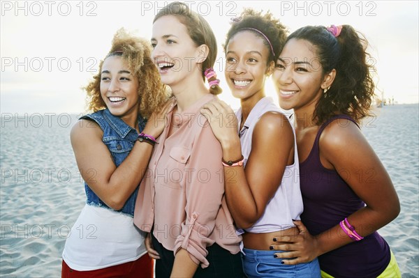 Smiling friends hugging at beach