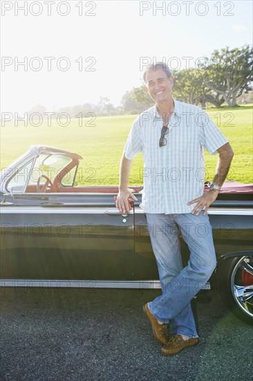 Caucasian man smiling near classic convertible