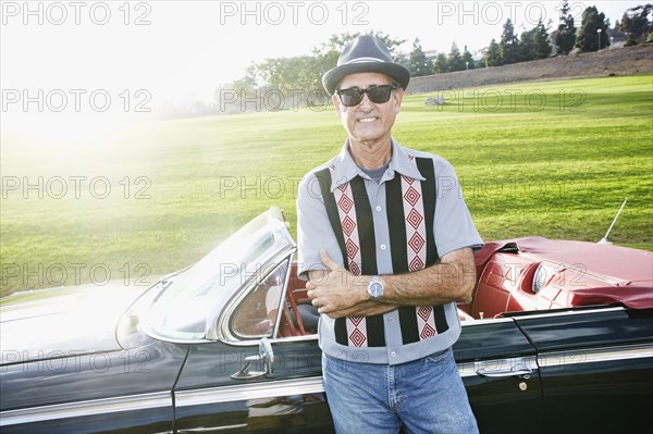 Mixed race man smiling near classic convertible