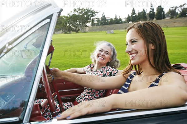 Mother and daughter driving in classic convertible