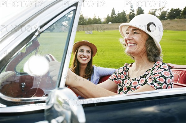 Mother and daughter driving in classic convertible