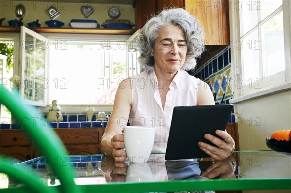 Caucasian woman using digital tablet in kitchen
