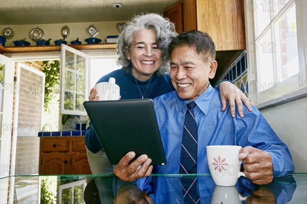 Couple using digital tablet in kitchen