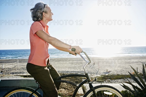 Caucasian woman riding bicycle near beach