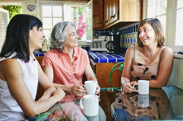 Caucasian mother and daughters drinking coffee in kitchen