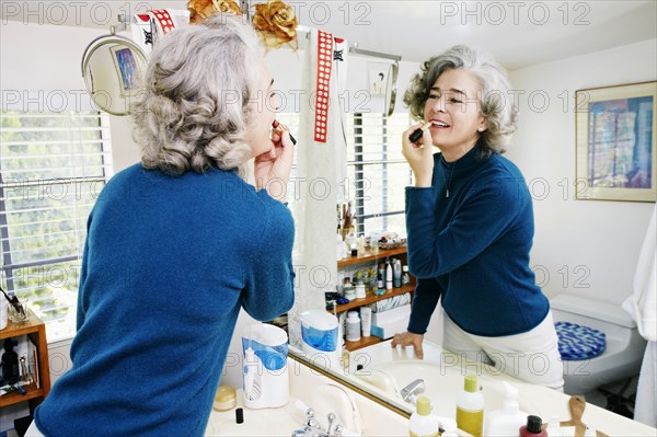 Caucasian woman applying makeup in mirror