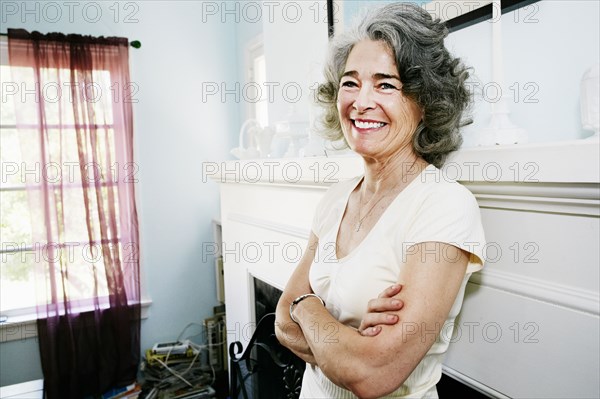 Caucasian woman standing with arms crossed in living room