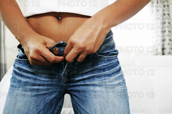 Hispanic woman buttoning jeans