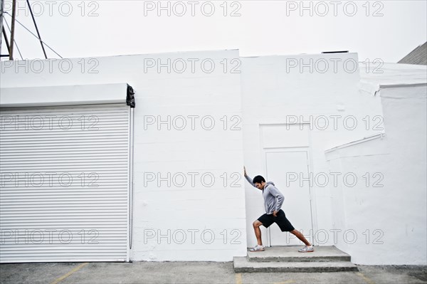 Mixed race man stretching in doorway