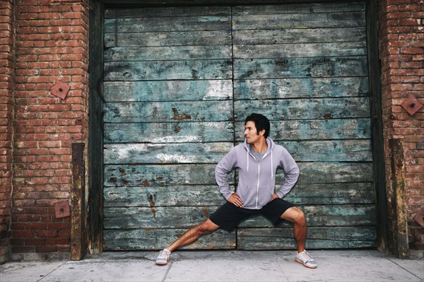 Mixed race man stretching near industrial building