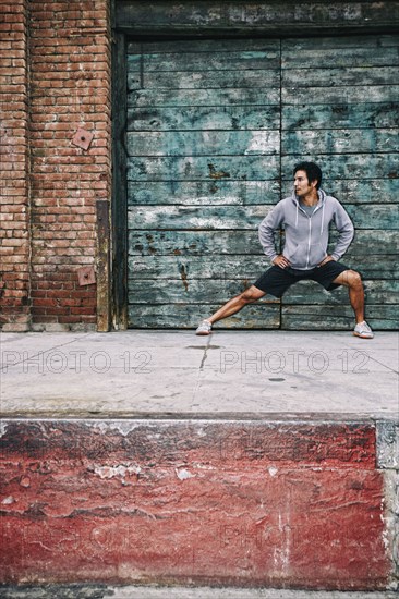 Mixed race man stretching near industrial building