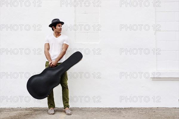 Mixed race musician carrying guitar case