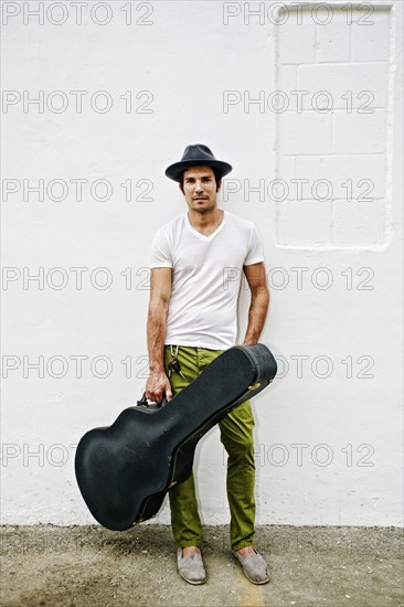 Mixed race musician carrying guitar case