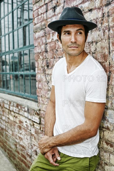 Mixed race man leaning on industrial building