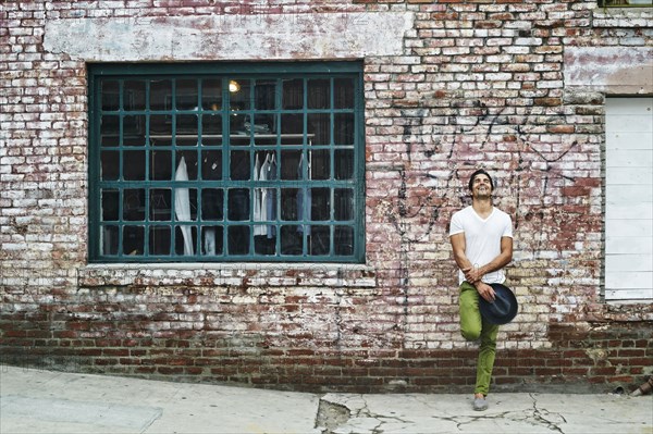 Mixed race man leaning on industrial building