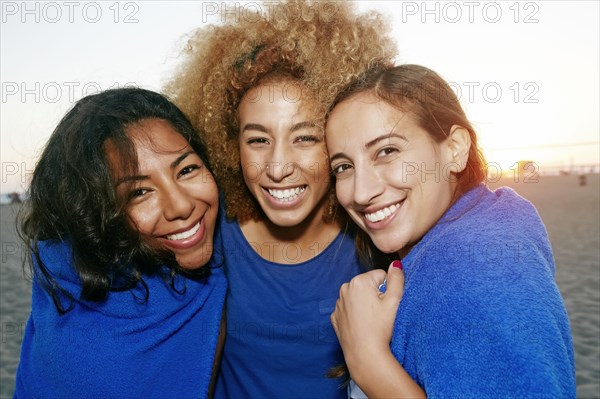 Hispanic women wrapped in blanket on beach