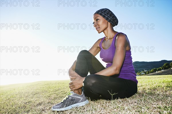 African American woman sitting on lawn in park