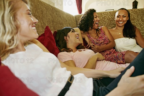 Smiling women laughing on sofa