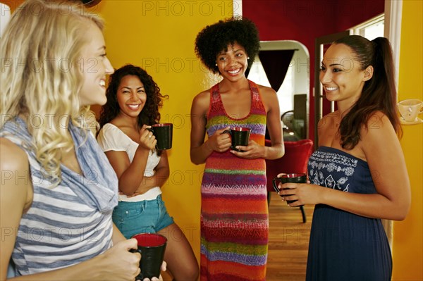 Smiling women drinking coffee together