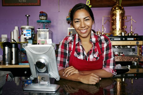 Hispanic barista smiling in coffee shop