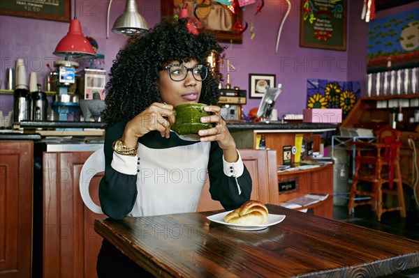 Mixed race woman drinking coffee in cafe