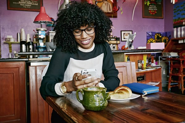 Mixed race woman using cell phone in cafe