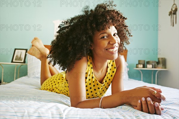 Smiling mixed race woman laying on bed