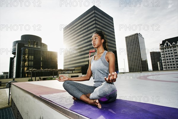 African American woman meditating on urban rooftop