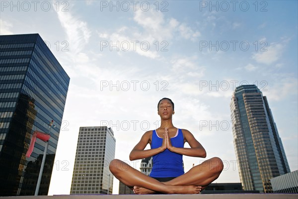 African American woman meditating on urban rooftop