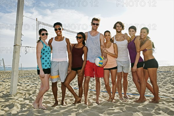 Friends smiling near volleyball net on beach