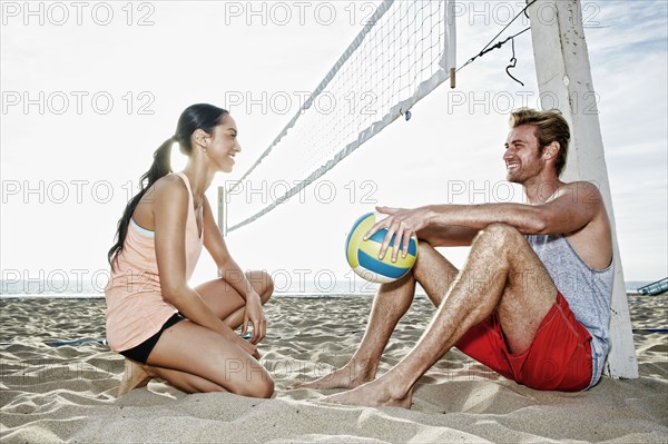 Friends talking near volleyball net on beach