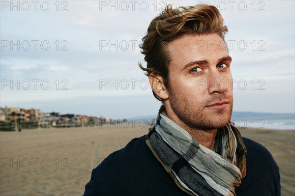 Serious Caucasian man standing on beach