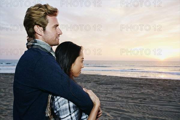 Couple hugging on beach at sunset