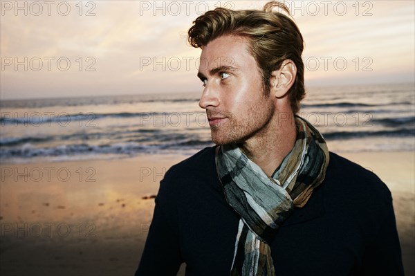 Serious Caucasian man standing on beach