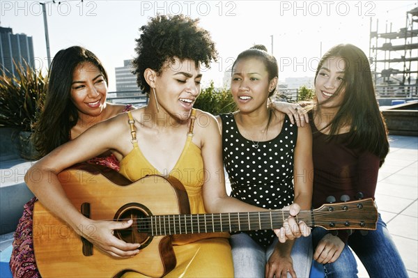 Women playing music and singing on urban rooftop