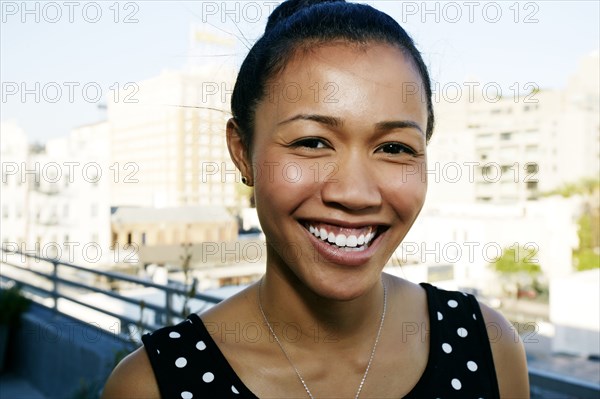 Mixed race woman smiling on urban rooftop