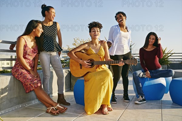 Women playing music and singing on urban rooftop