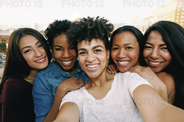 Smiling women taking selfie on urban rooftop