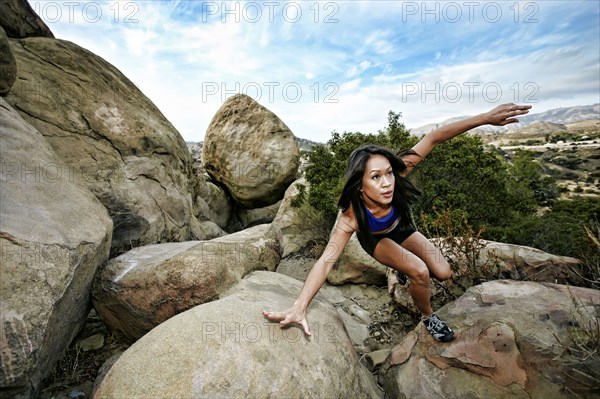 Vietnamese woman climbing on rocky hillside