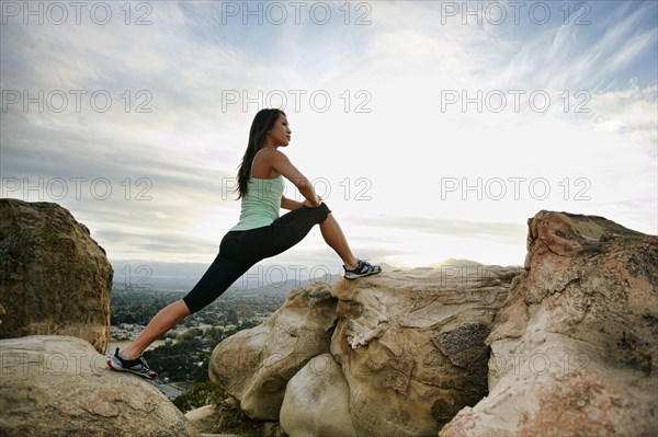 Vietnamese woman stretching on rocky hilltop