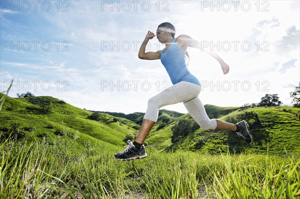 Black athlete running on rural hilltop