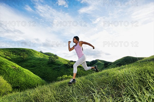 Black athlete running on rural hillside