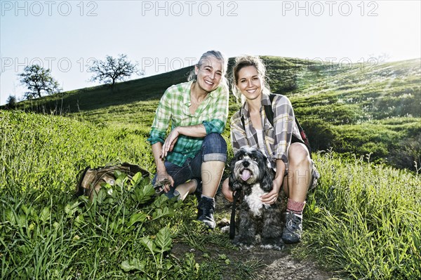 Caucasian mother and daughter walking dogs on grassy hillside