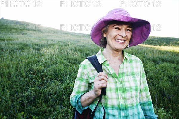 Older Caucasian woman smiling on grassy hillside