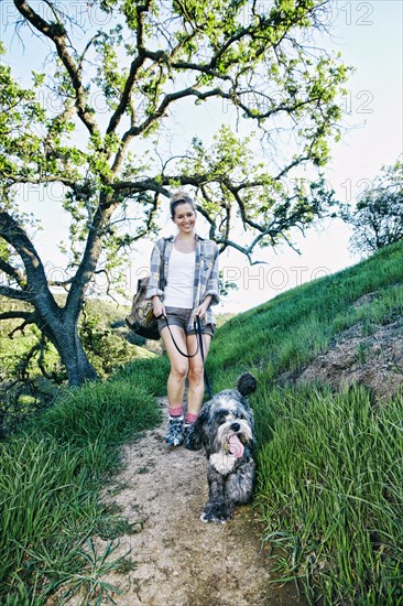 Caucasian woman walking dog on grassy hillside