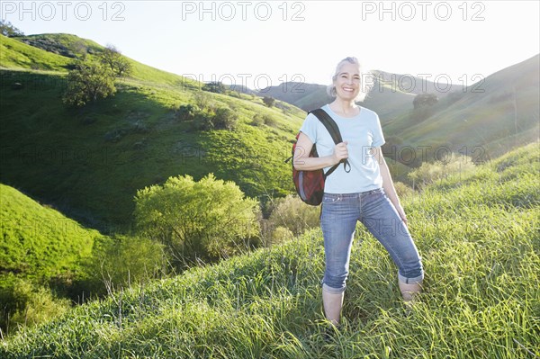 Older Caucasian woman smiling on grassy hillside